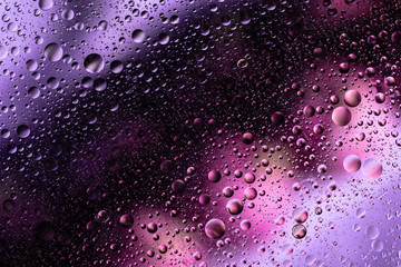 water drops on glass with purple and pink background, close-up 