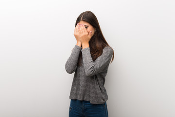 Teenager girl on isolated white backgorund covering eyes by hands and looking through the fingers