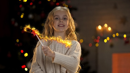 Adorable girl with magic wand making miracles, little fairy fulfilling wishes