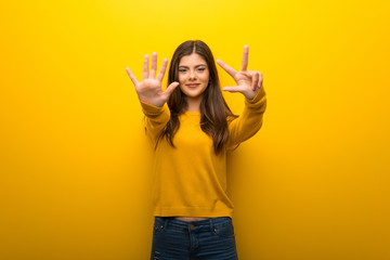 Teenager girl on vibrant yellow background counting eight with fingers