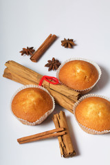 Fresh tasty muffins. Nearby are cinnamon sticks and anise stars. On a white background.
