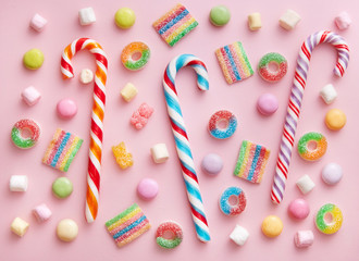 Candy selection and candy canes viewed from above. Variation of sweets on a pink background. Top view