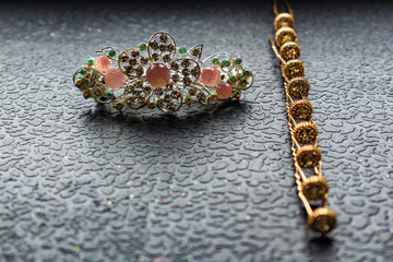 Beautiful automatic barrette with shiny stones and pink beads on dark textured background. Gold hairpins with white rhinestones. Set of jewelry and accessories for women.