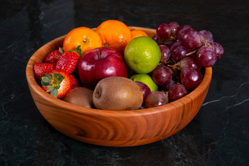 Healthy food: mix from fruits in bowl, old marble background, selective focus