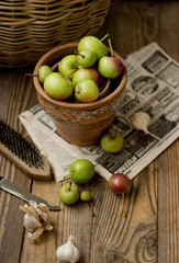 Green apples in a clay pot on a wooden background