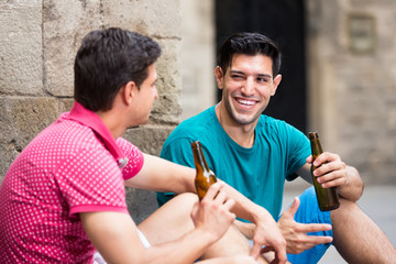 satisfied male fans are drinking beer and talking about football outdoor in Barcelona