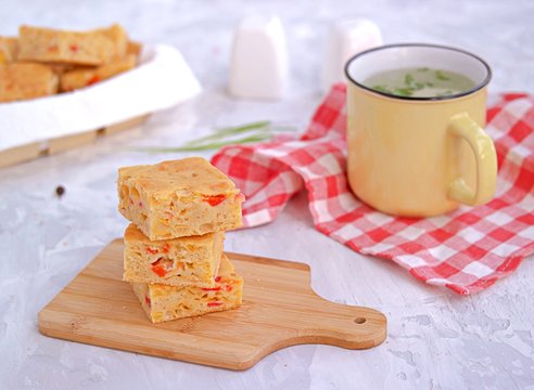 Slices of traditional American corn bread with cheddar cheese and sweet peppers on a gray background.