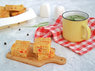 Slices of traditional American corn bread with cheddar cheese and sweet peppers on a gray background.