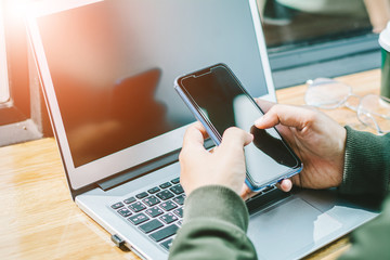 Young Asian businessman is working on smart phone in office with laptop. Online shopping.