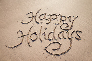 Happy Holidays message handwritten in smooth sand under tropical sun