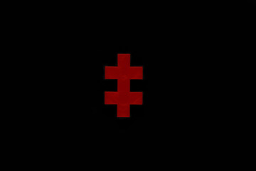 Red puzzle piece or two-barred cross isolated on black background