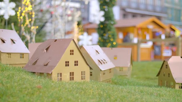 Handmade small white folded cardboard houses with illuminated windows on gren lawn background. Winter decoration. Christmas, Architecture and business real estate concept.