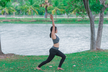 Slim girl play yoga on the lawn at the park,relax in nuture,Asian Girls love health practicing yoga