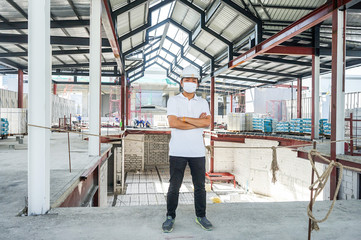 Fototapeta premium Asian guy stand on site constrcution with helmet and mask., Bangkok, Thailand.