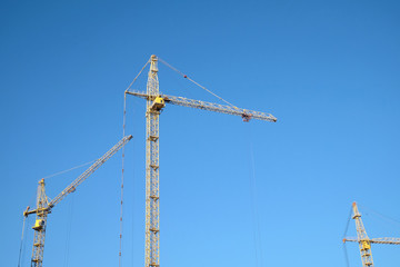 Big yellow construction tower crane over clear blue as background, sky horizontal photo