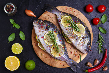 Sea bream or dorado  fish with lemon, herbs, vegetables and spices. Flatlay, overhead