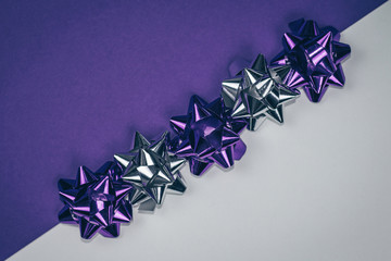 Christmas ornament of several violet and silver shiny decorations lined diagonally on violet and white background.