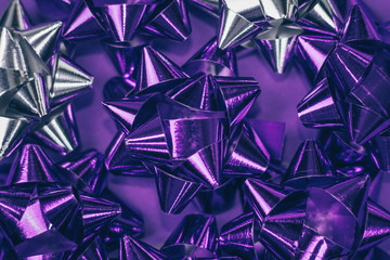 Christmas ornament of several violet and silver shiny decorations on violet background.