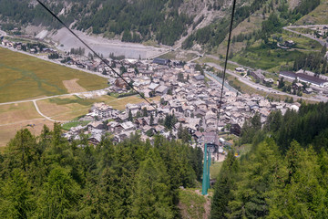 Fototapeta na wymiar Elevated view from a cable car of a mountain valley in summer with an alpine village and green forest, Cogne, Aosta Valley, Alps, Italy 