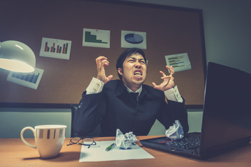 Asian businessman under stress due to excessive work,Feeling exhausted,Young clerk has a problem in a office,sad man from work,Angry messy man concept