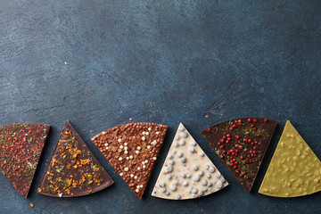 Triangle shape chocolate pizza slices with diverse kinds of toppings on blue background, top view