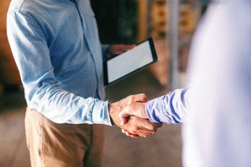 Close up of two businessmen shaking hands in warehouse.