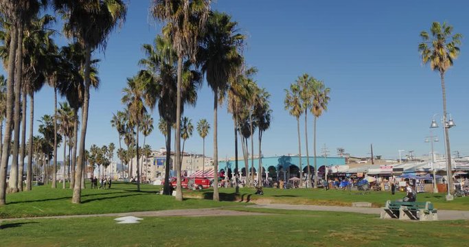 VENICE BEACH, CA - Circa December, 2018 - A daytime exterior establishing shot of people enjoying the boardwalk of Venice Beach.  	