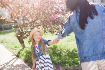 Young mother and her little daughter having fun in spring time. Beautiful mum and cute girl walking outdoor. Happy family together