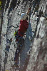 Girl climber climbs on a vertical rock wall close-up.