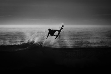 silueta de un surfista en blanco y negro y a contraluz	