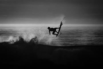 silueta de un surfista en blanco y negro y a contraluz	