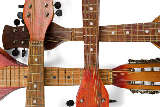 The crossed fingerboards of four old mandolins. Isolated on white background.