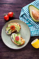 Toasts with avocado pieces, cherry tomatoes, scrambled eggs and soft cream cheese.