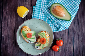 Toasts with avocado pieces, cherry tomatoes, scrambled eggs and soft cream cheese.