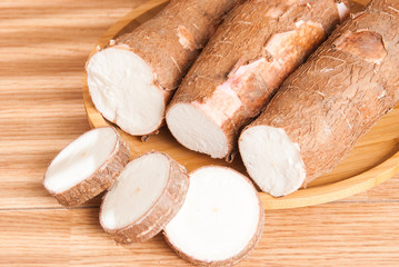 Raw cassava tuber on wooden background - Manihot esculenta