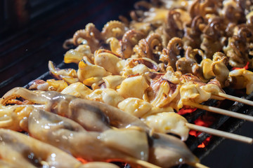 Grilled squid in a stick at the street food in china town thailand