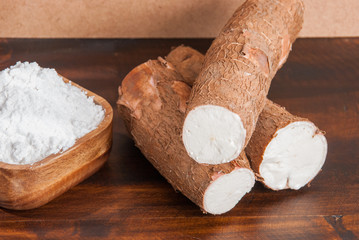 Raw cassava tuber on wooden background - Manihot esculenta
