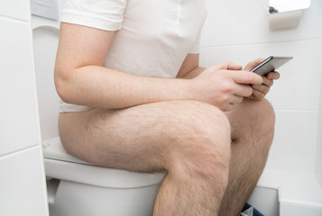Obraz na płótnie Canvas Man using tablet pc in the toilet.