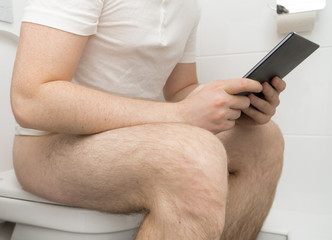 Man using tablet pc in the toilet.