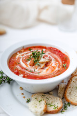 Tomato soup on white with cream and herbs. Top view, copy space