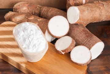 Raw cassava tuber on wooden background - Manihot esculenta