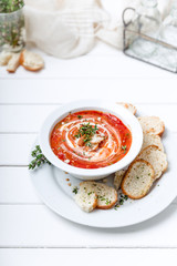 Tomato soup on white with cream and herbs. Top view, copy space
