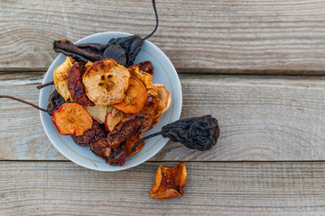 Mix of dried fruits in a plate on wooden table. Top view