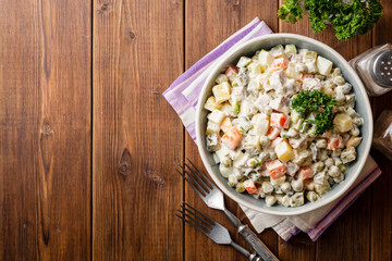 Traditional Russian salad Olivier in bowl on wooden table. Top view. Copy space.