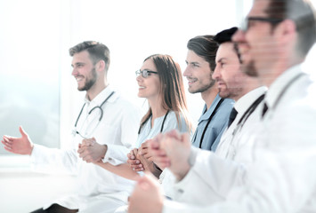 doctors sit in a row and hold hands of each other