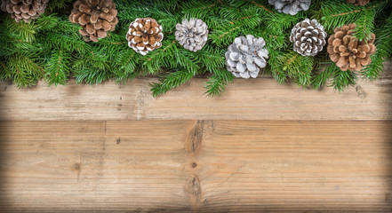 Christmas garland with pine cones on wooden background. Space for text.