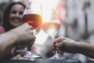Friends toasting with wine outdoor - focus on glasses