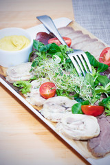 Fresh salad with delicious chicken breast, ruccola, spinach, cabbage, arugula, parmesan and cherry tomato on wooden background. Oil, salt and pepper. Healthy and diet food concept