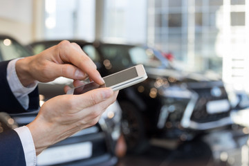 Man using mobile smart phone at dealer showroom.