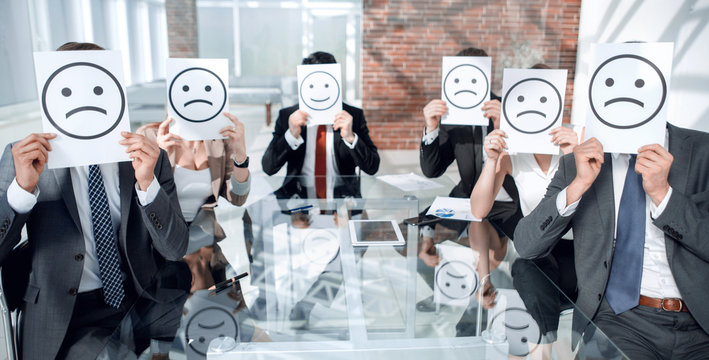 Image of businessman holding drawing of upset face.